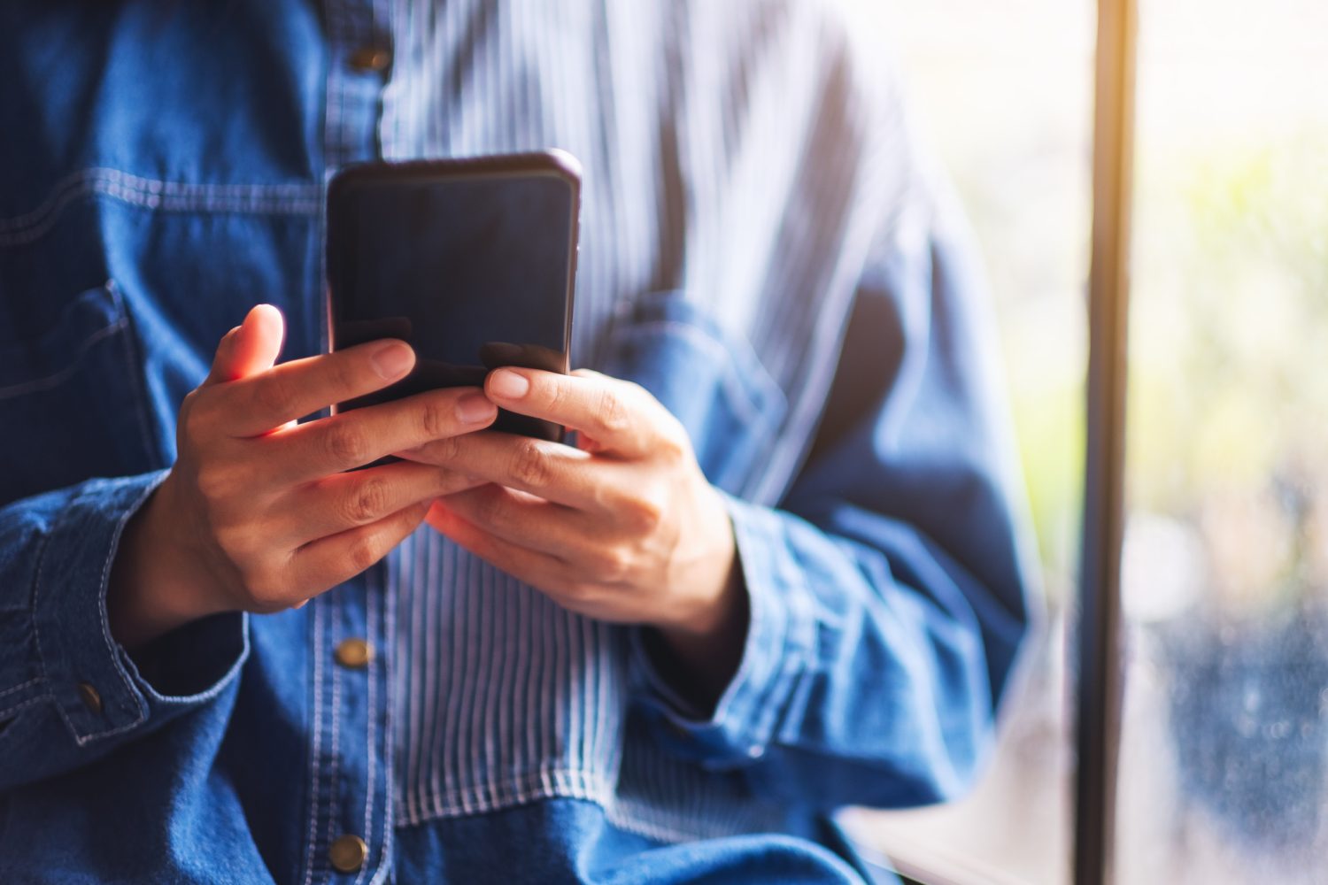Closeup image of a woman holding and using mobile phone
